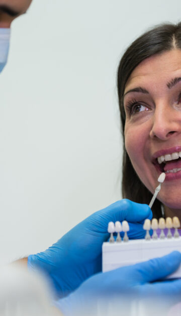 Dentist examining female patient with teeth shades at dental clinic